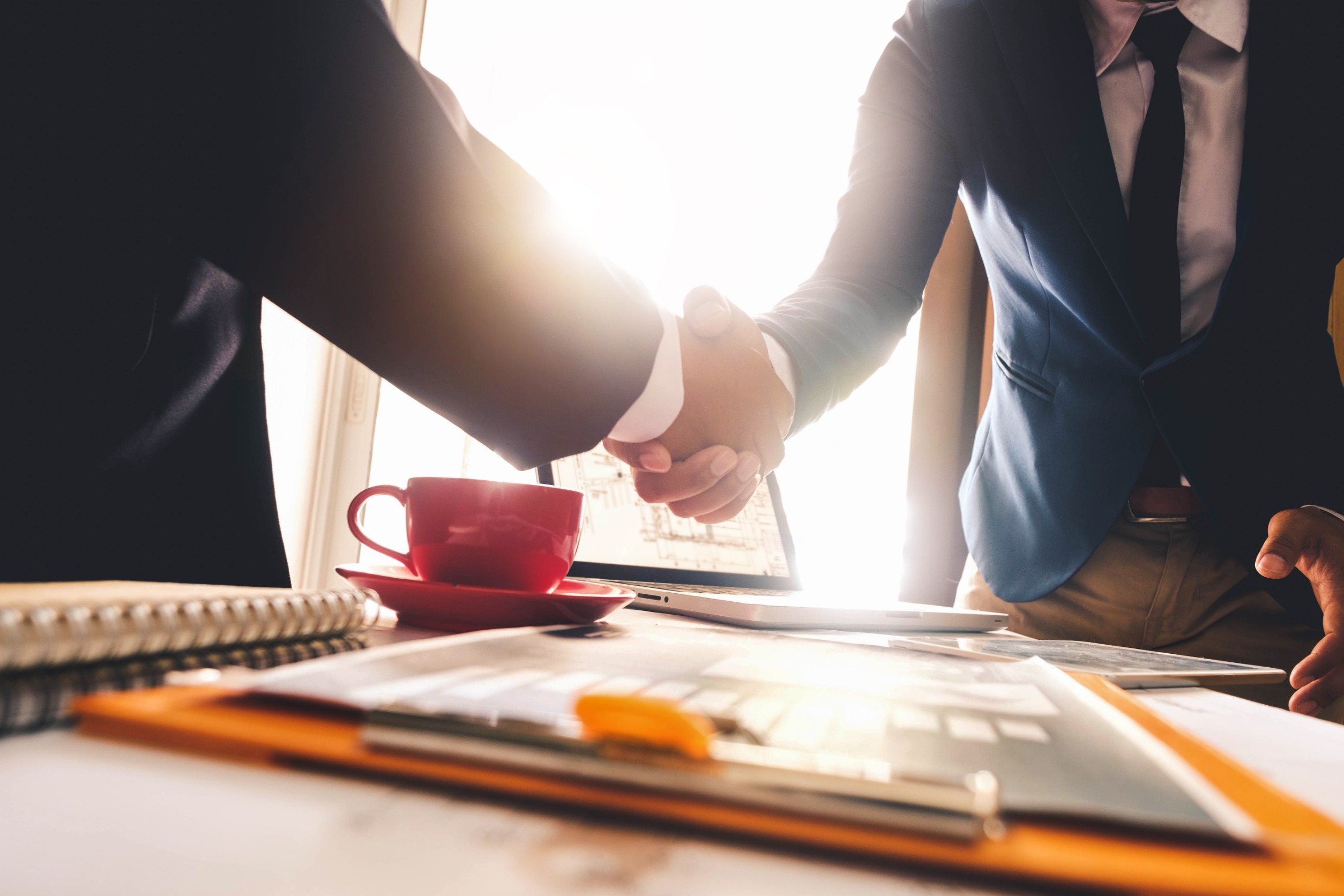 Two confident business man shaking hands during a meeting in the office, success, dealing, greeting and partner in sun light